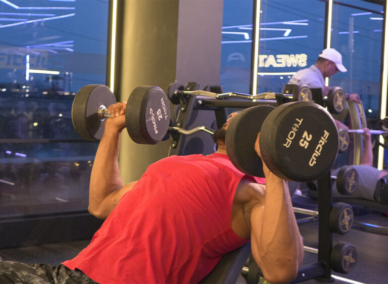 Man lifting dumbbells on an incline bench during a workout at the gym.