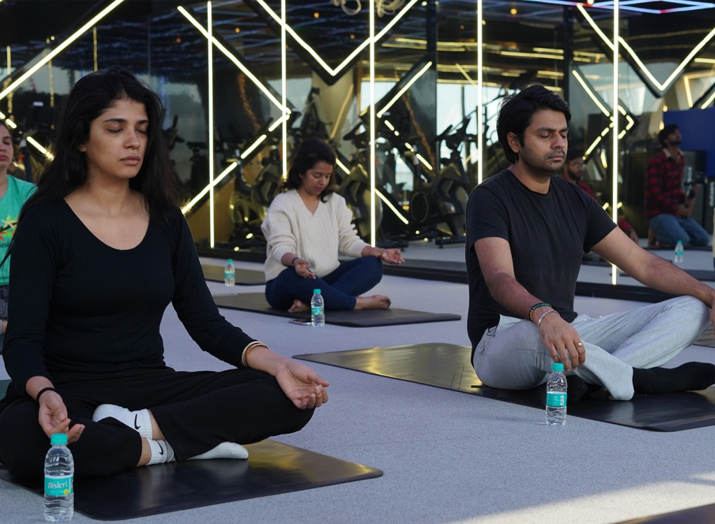 “Group of people practicing yoga meditation indoors on mats, sitting cross-legged with eyes closed.”