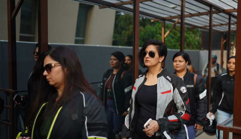 "A group of women bikers dressed in riding jackets, with one woman in the front wearing sunglasses and holding a phone, participating in FitClub™’s Mother’s Day rally in Gurgaon celebrating empowerment and motherhood."