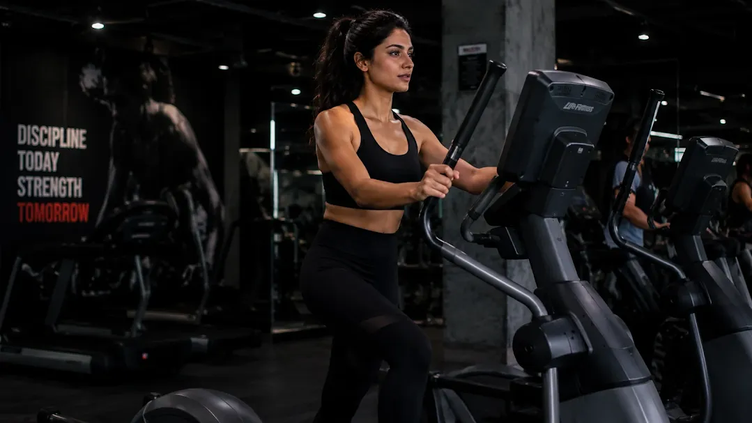 Woman performing cardio exercises in gym on an elliptical machine during an intense fitness workout session.